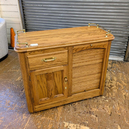 Wooden sideboard with brass handles on a concrete floor.