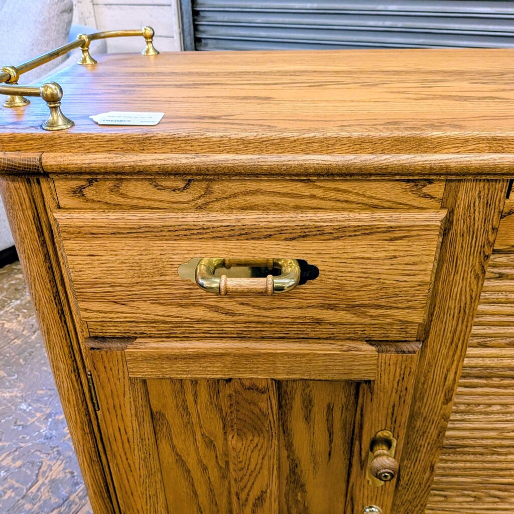 Wooden desk with brass handles on a textured floor.