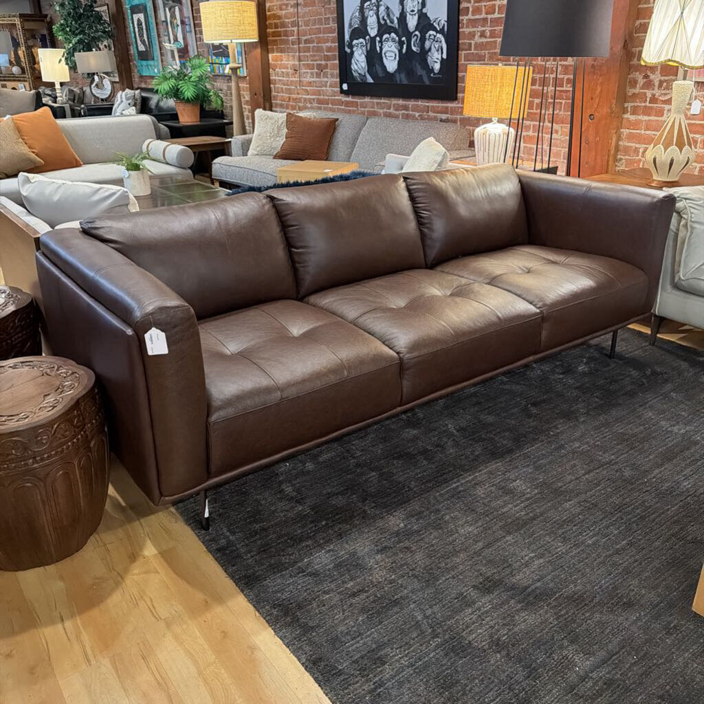 Brown leather sofa in a living room setting with decor elements.