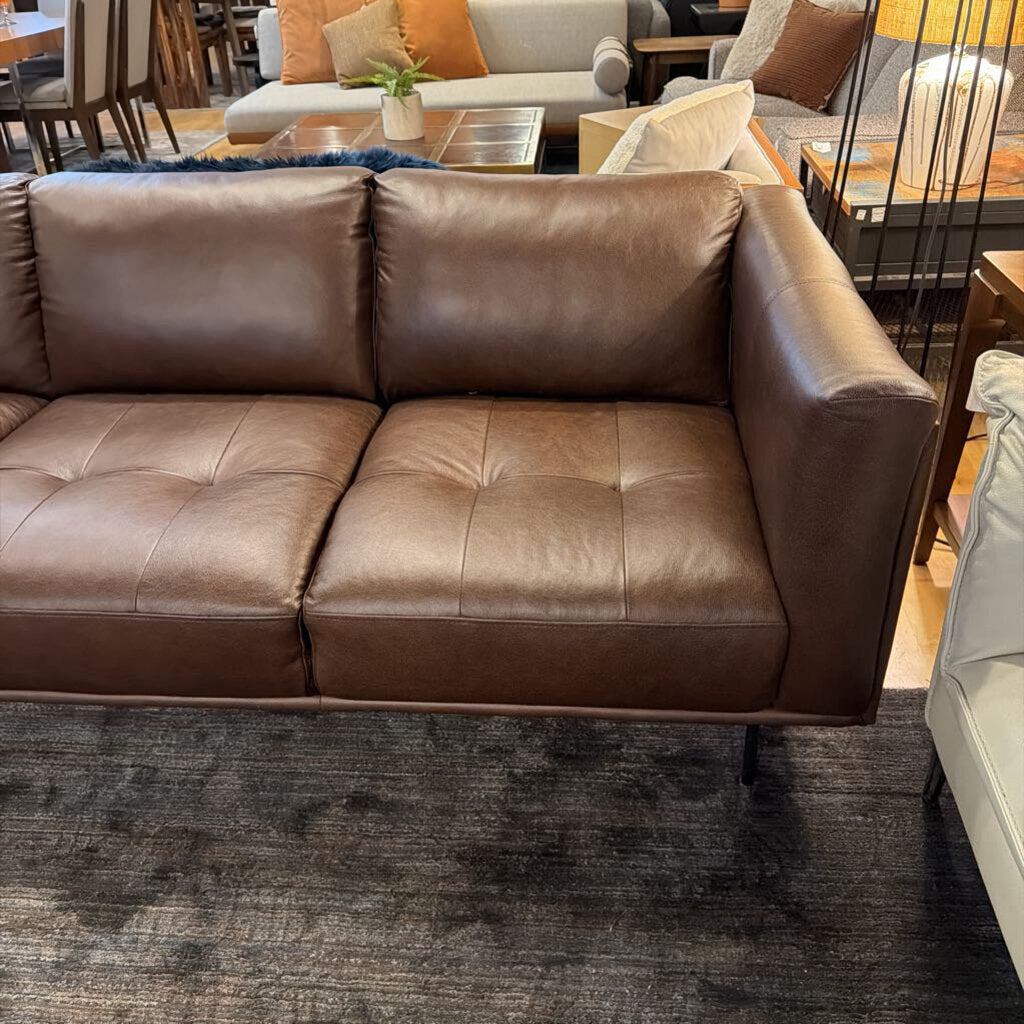 Brown leather sofa in a living room setting with other furniture.