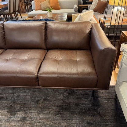 Brown leather sofa in a living room setting with other furniture.