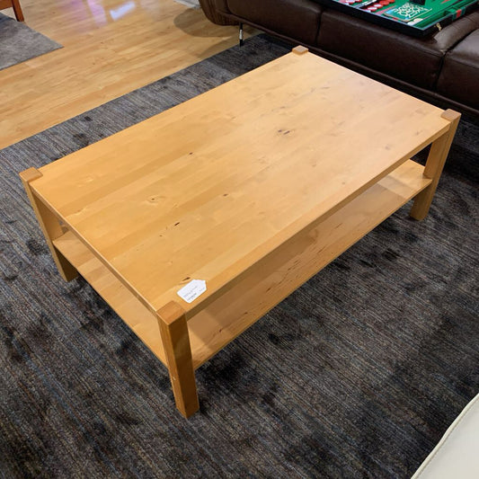 Wooden coffee table in a room with a rug and furniture.