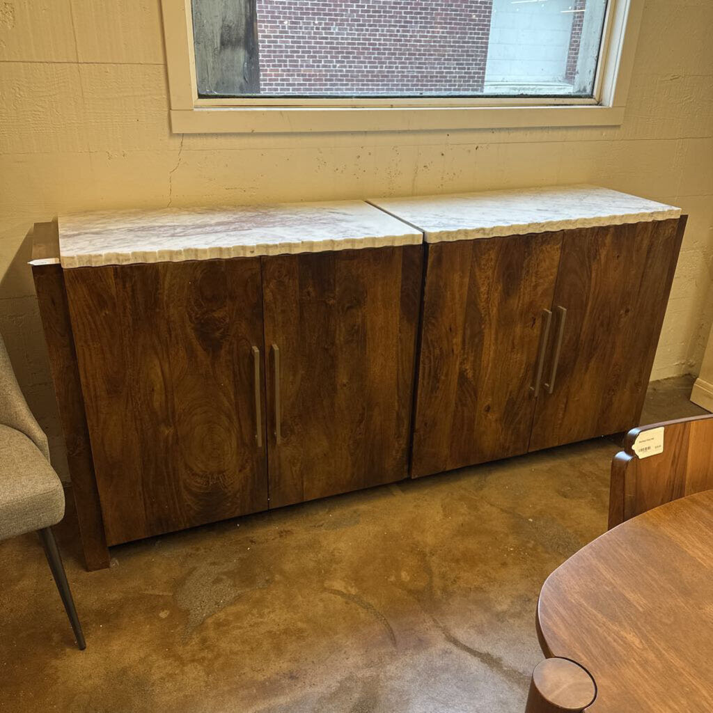 Wooden cabinet with marble top in a room with a window and chair.