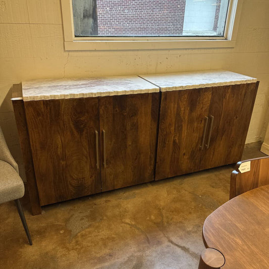 Wooden cabinet with marble top in a room with a window and chair.