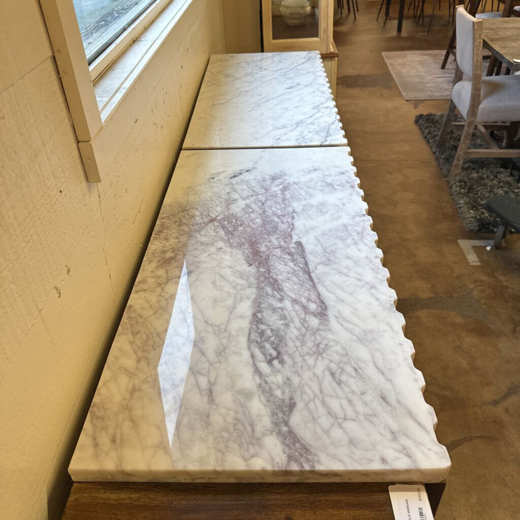 Two marble slabs on a wooden floor with a window in the background