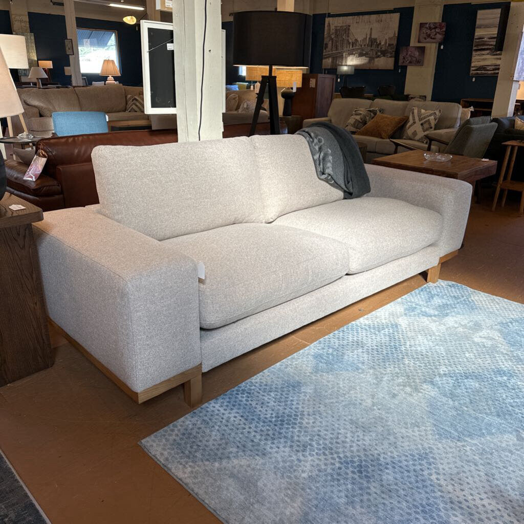 Light gray sofa in a showroom with a blue patterned rug on the floor.