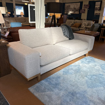 Light gray sofa in a showroom with a blue patterned rug on the floor.