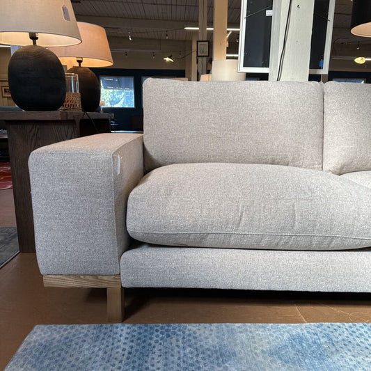 Gray sofa in a store setting with lamps and furniture in the background