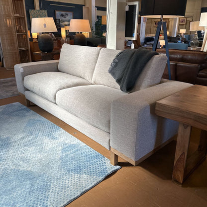 Gray sofa in a room with a blue rug and wooden coffee table
