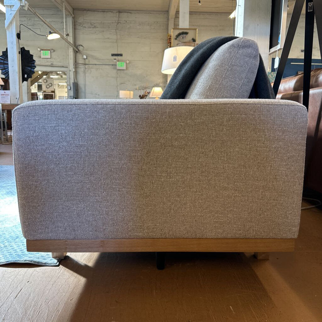 Gray upholstered chair with wooden legs in a showroom setting