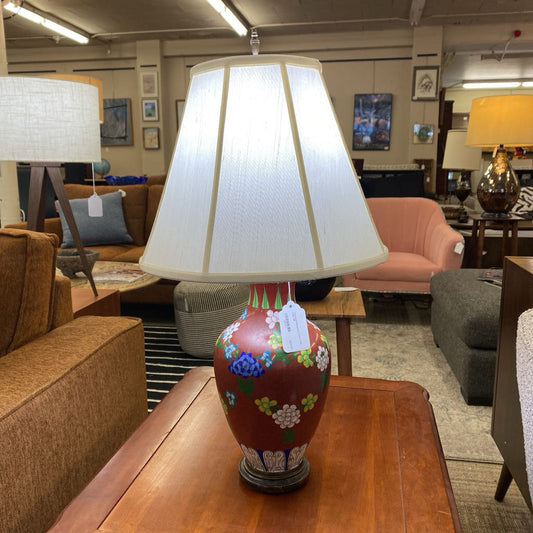 Decorative lamp with floral design on a wooden table in a furniture store.