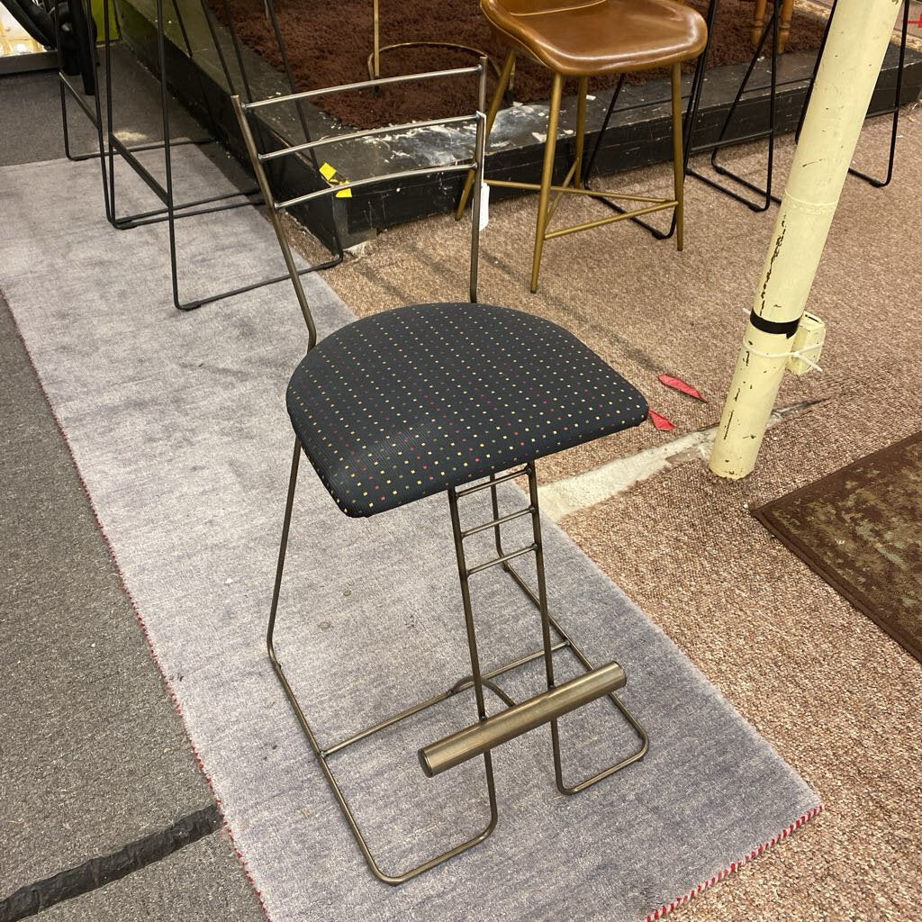 Bar stool with black cushioned seat on a gray rug
