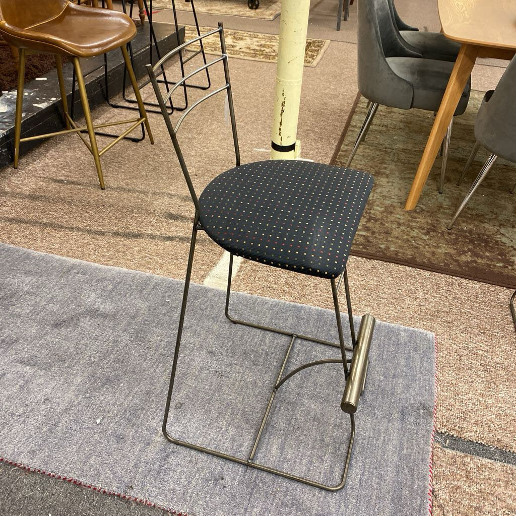 Chair with a black cushioned seat on a gray rug in a room with other chairs and tables.