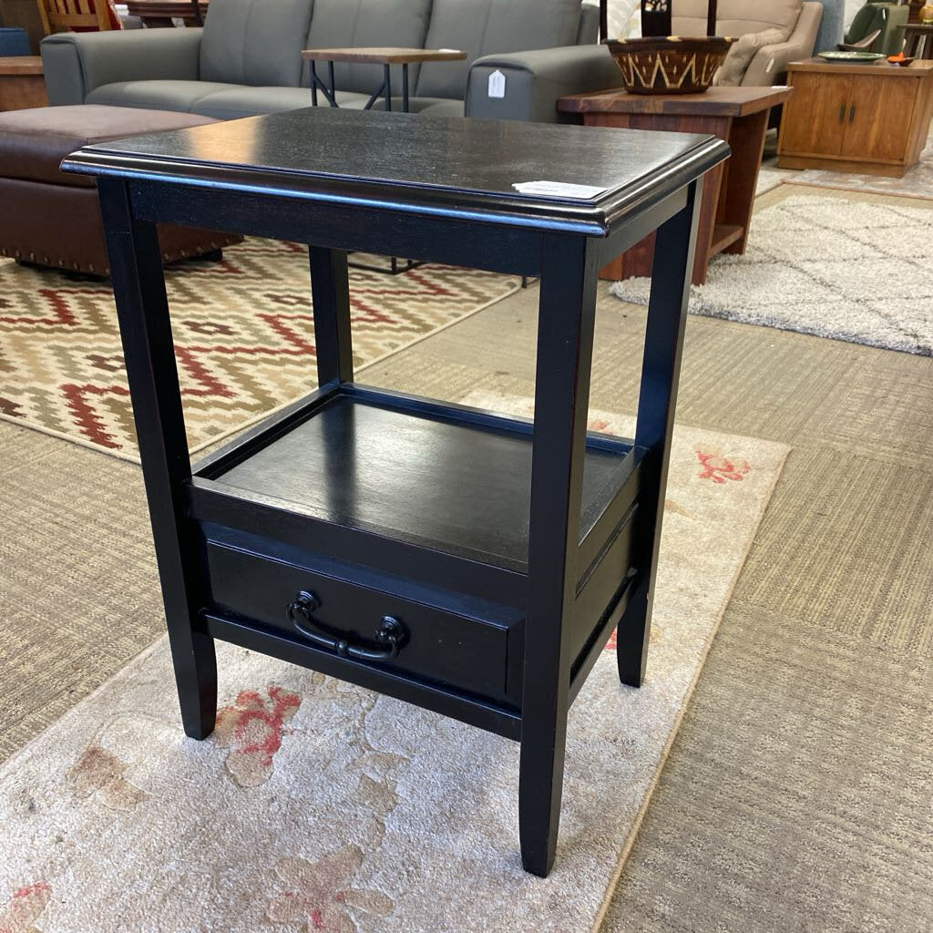 Black side table with a drawer in a furniture store setting