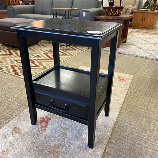 Black side table with a drawer in a furniture store setting