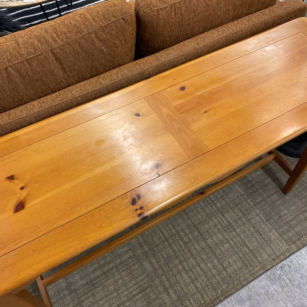 Wooden bench in front of a brown sofa on a carpeted floor
