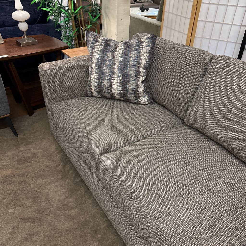 Gray sofa with a patterned pillow in a living room setting