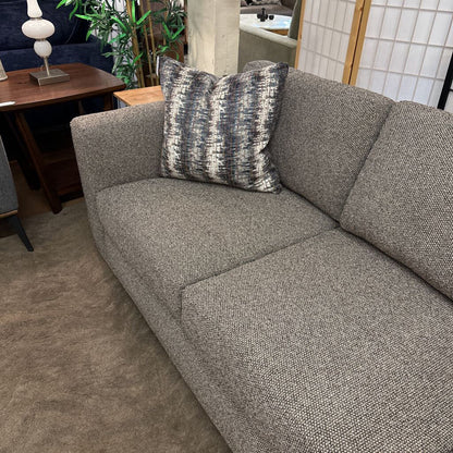 Gray sofa with a patterned pillow in a living room setting