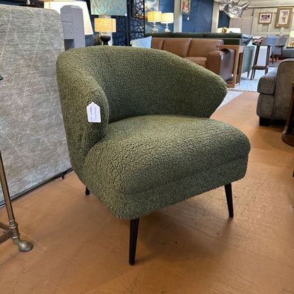 Green textured armchair in a showroom setting with other furniture.