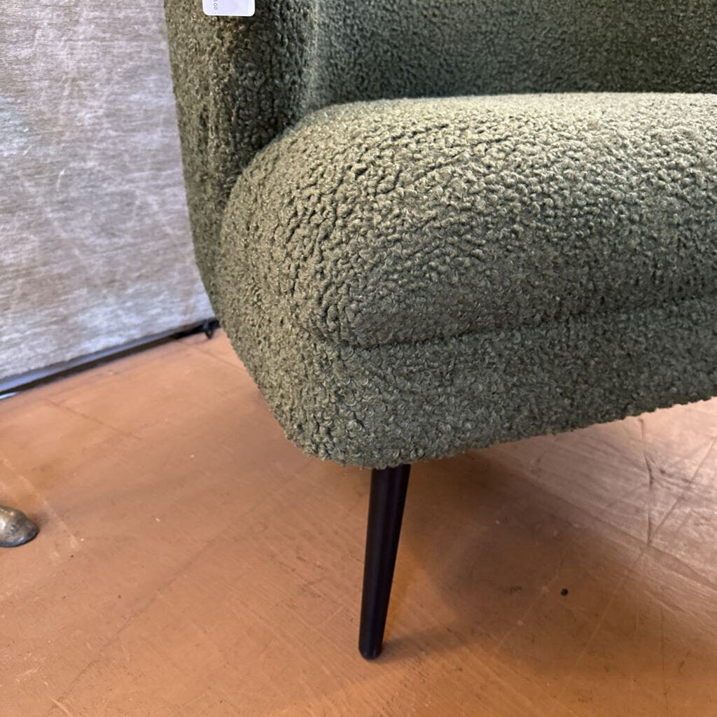 Green textured armchair with a wooden floor and neutral wall background