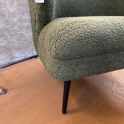 Green textured armchair with a wooden floor and neutral wall background
