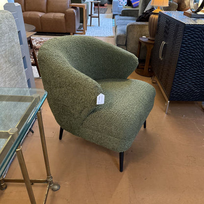 Green textured armchair in a showroom setting with other furniture.
