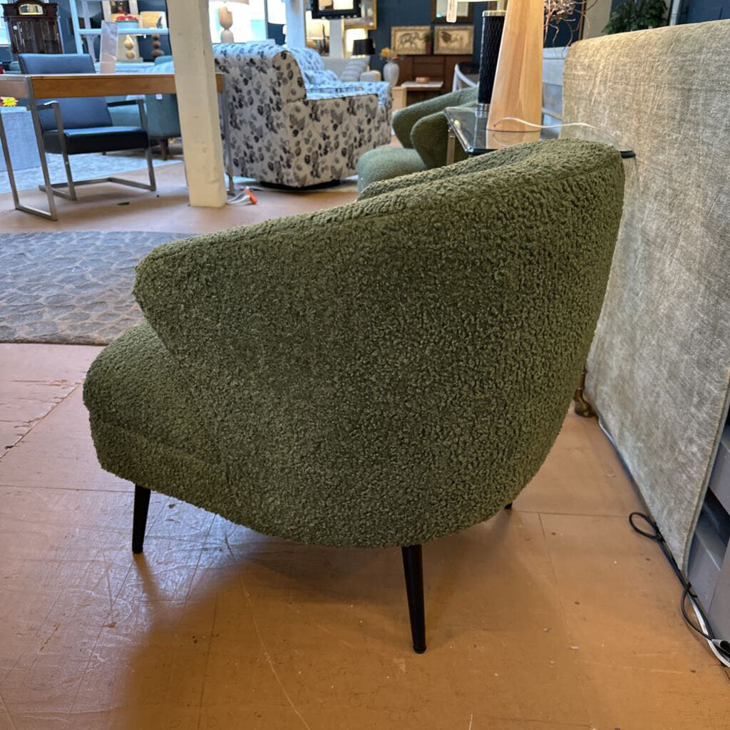 Green textured armchair in a showroom setting with other furniture.