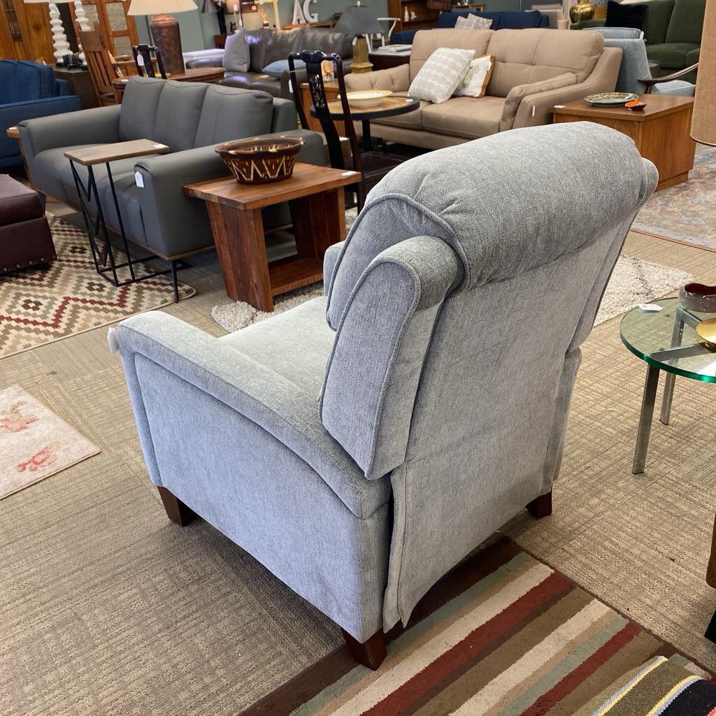 Gray armchair in a furniture store with other seating options in the background.