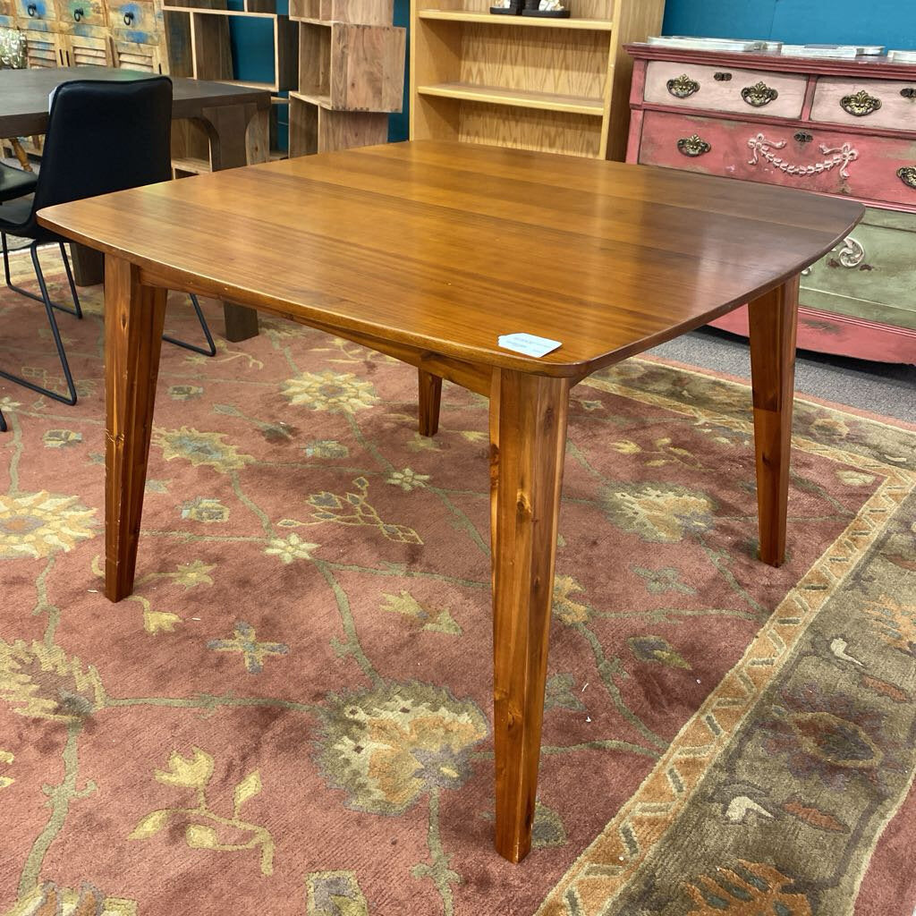 Wooden dining table in a room with furniture and a patterned rug.
