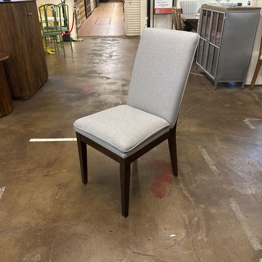 Gray upholstered chair on a concrete floor in an indoor setting