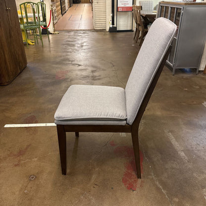Gray cushioned chair on a concrete floor in an indoor setting