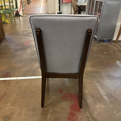 Chair with gray backrest and wooden frame on a concrete floor.
