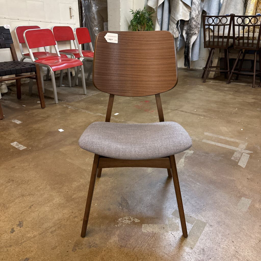 Wooden chair with gray cushioned seat in a storage or warehouse setting