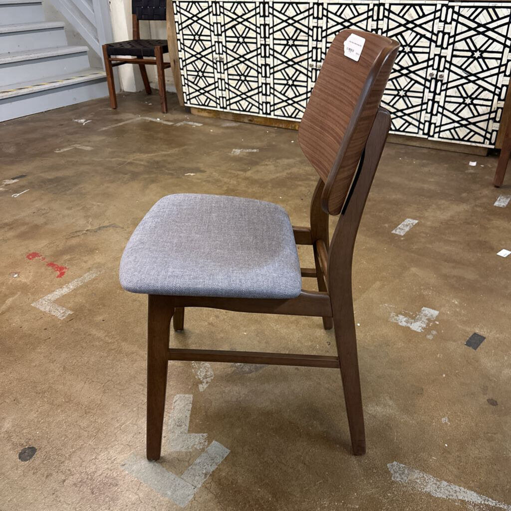 Wooden chair with gray cushioned seat on a brown floor.