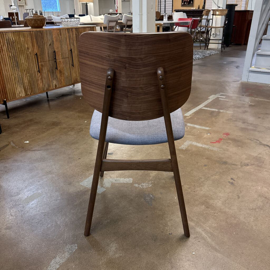 Wooden chair with a gray cushion on a concrete floor in an indoor setting