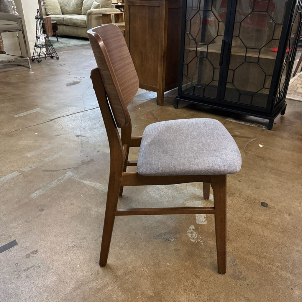 Chair with wooden frame and gray cushioned seat on a concrete floor.