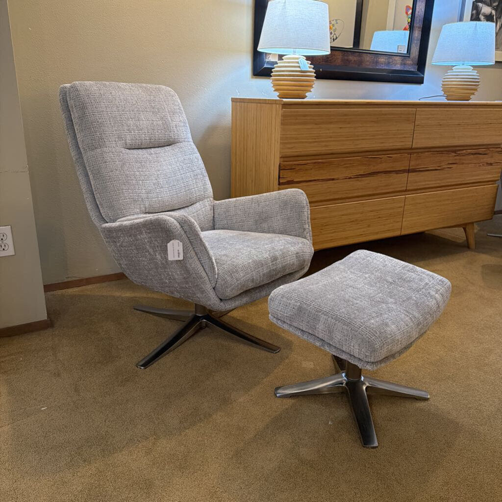 Gray recliner chair with ottoman in a room with wooden dresser and lamps.