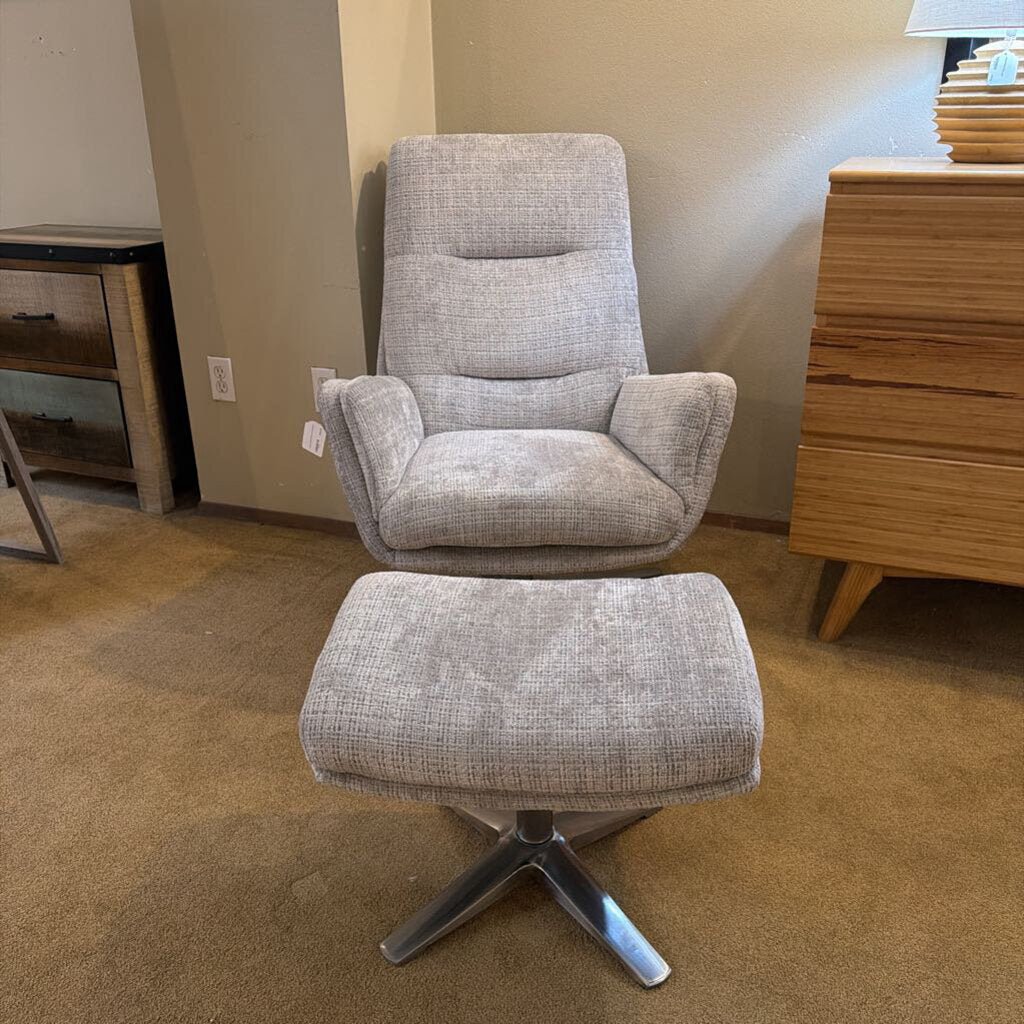 Gray upholstered chair with ottoman on a carpeted floor.