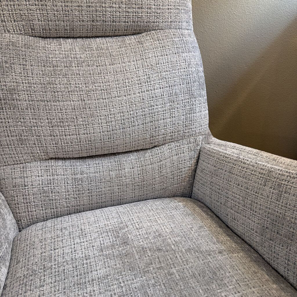 Gray textured armchair against a neutral wall