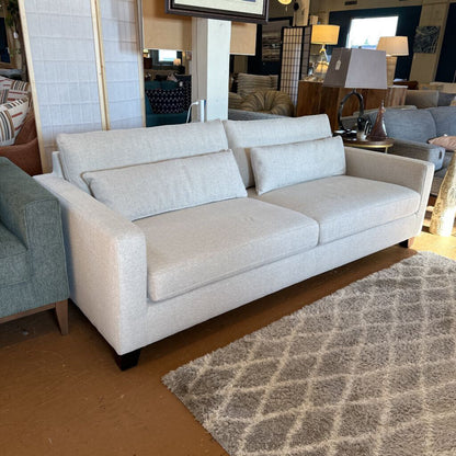 Light gray sofa in a showroom setting with other furniture and decor.