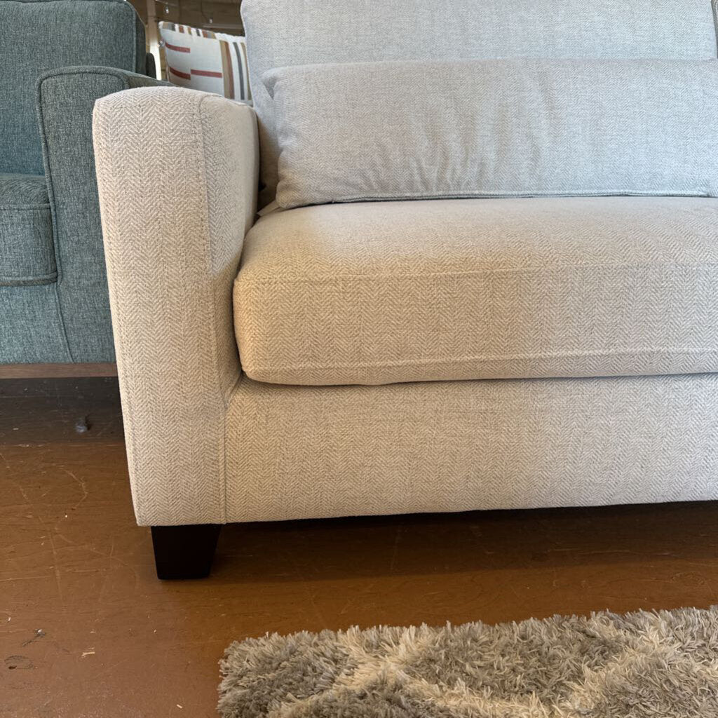 Beige sofa with a textured fabric on a wooden floor.