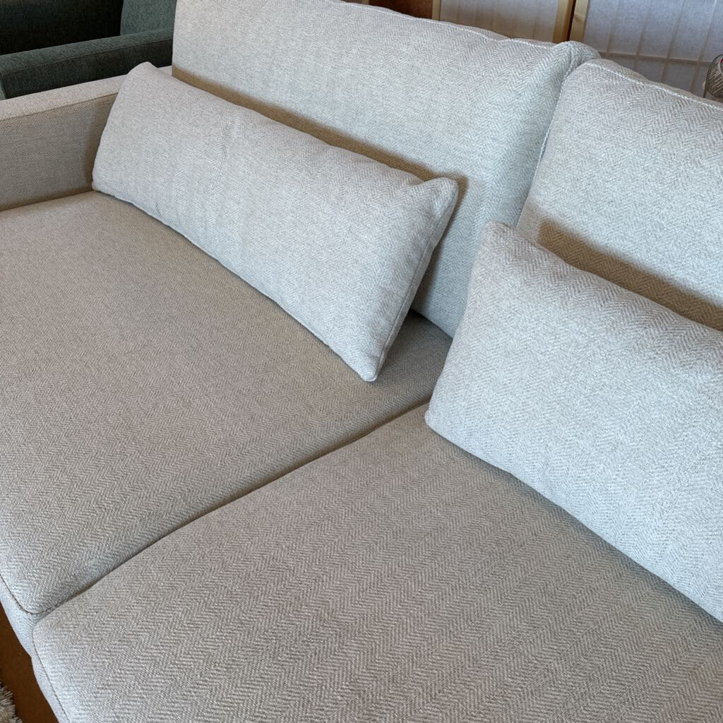 Beige sectional sofa with cushions in a neutral setting