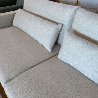 Beige sectional sofa with cushions in a neutral setting