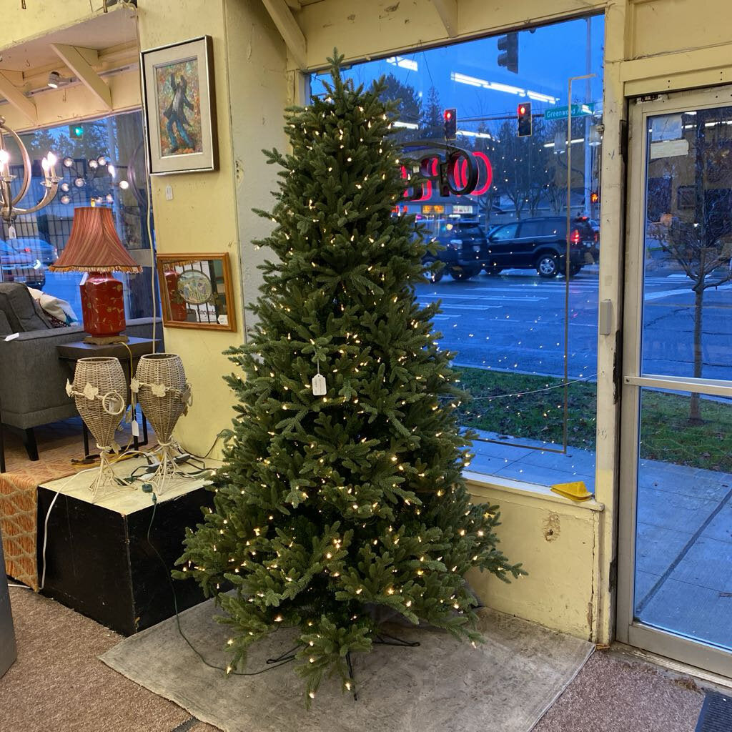 Decorative Christmas tree inside a store with a window view of street activity.