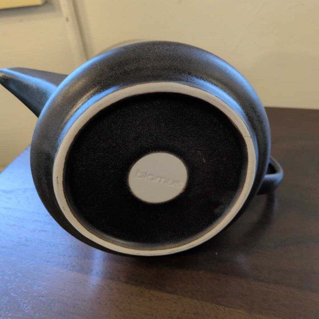 Black teapot with a visible brand logo on a wooden surface