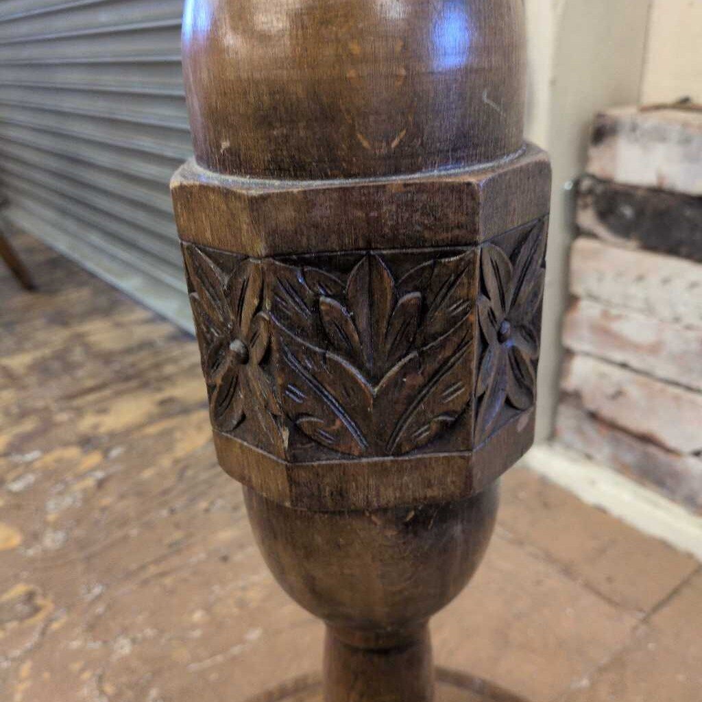 Carved wooden pedestal with floral patterns on a rustic background