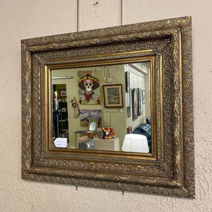 Decorative gold-framed mirror on a textured wall