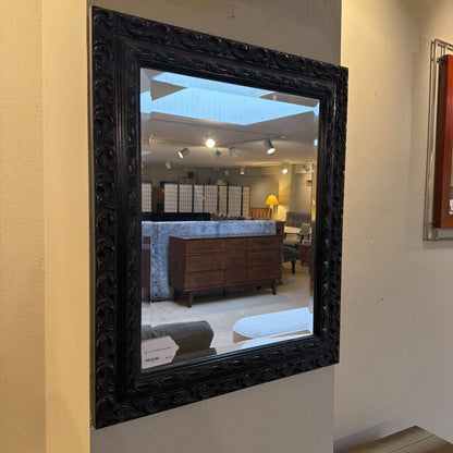 Decorative black-framed mirror on a wall