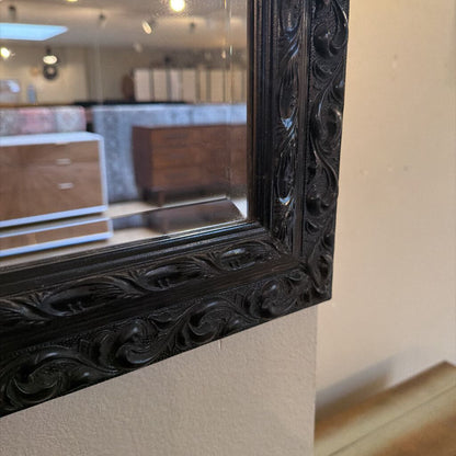 Decorative black framed mirror on a wall