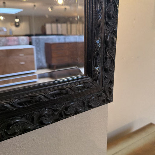 Decorative black framed mirror on a wall